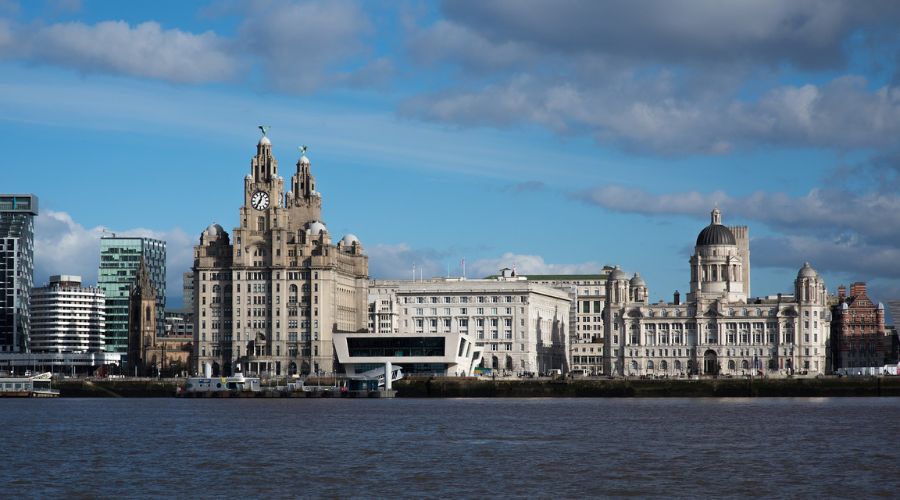 large white building next to a river mersey