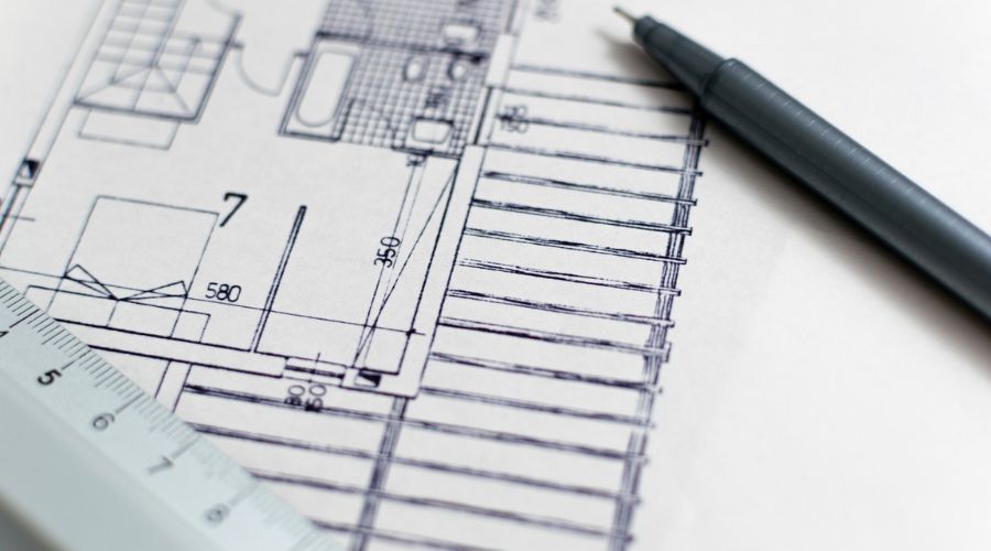 Image of an achitects' blueprint with a pen and ruler.