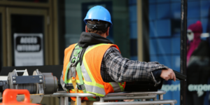 Photograph of the back of a construction worker with a blue hard hat.